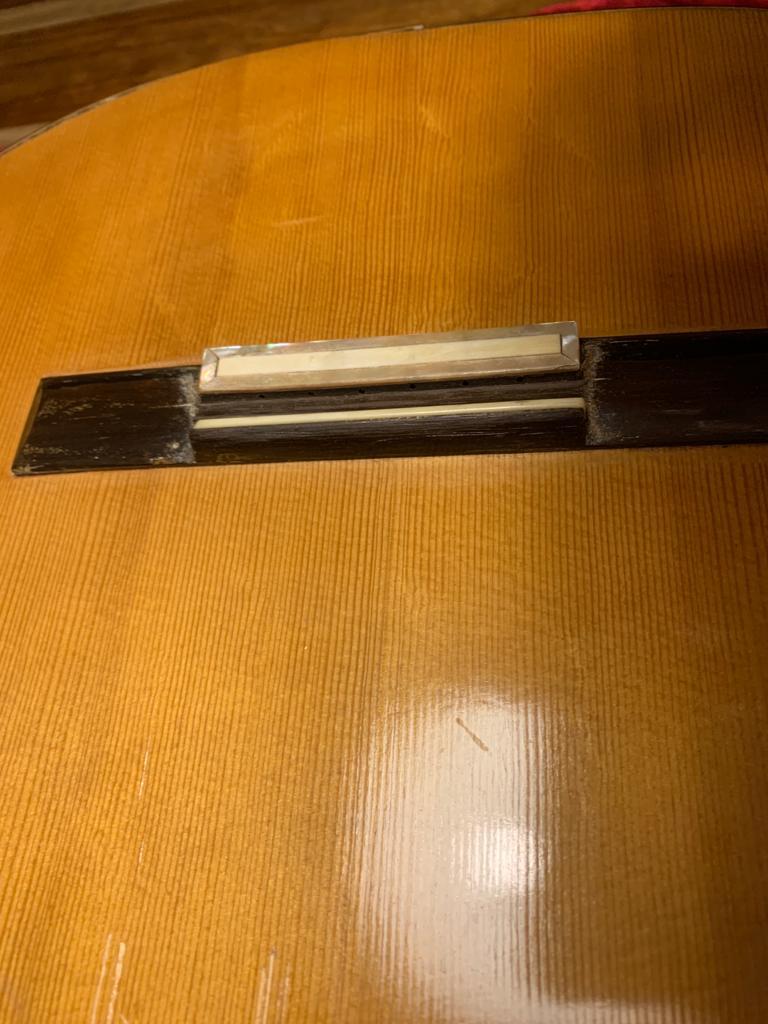 Using a thin blade to check a detached brace on the guitar back